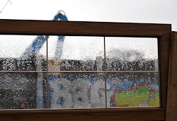 Kran hinter regenperlendem Fenster